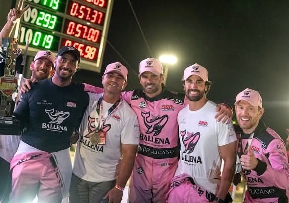 Equipe reunida com troféu ao lado do painel de tempos das 500 Milhas de Kart